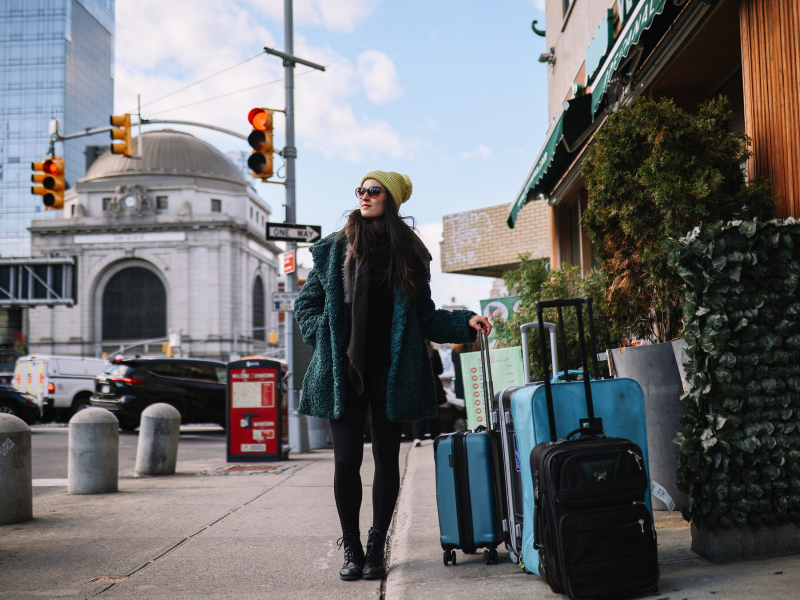 Reisende Frau kommt gerade in New York City an. Sie steht vor ihrem Hotel mit ihrem Gepäck und schaut sich um.